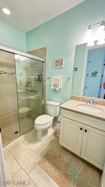 bathroom featuring tile patterned floors, vanity, toilet, and a shower with shower door