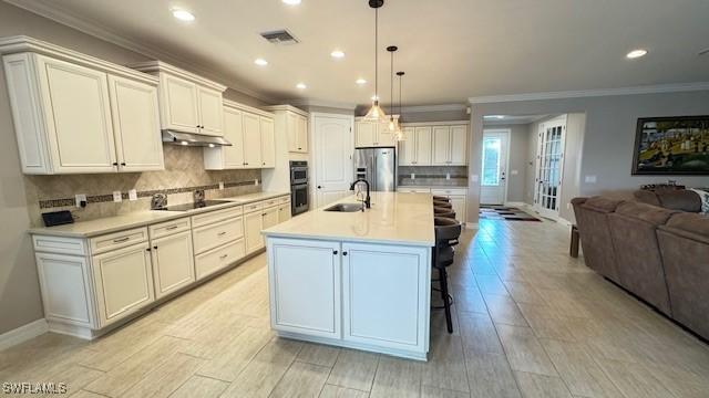 kitchen with pendant lighting, sink, black electric cooktop, an island with sink, and stainless steel fridge with ice dispenser