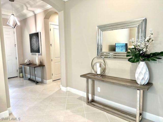 corridor featuring light tile patterned floors and crown molding