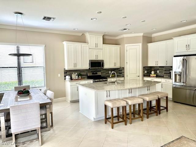 kitchen featuring a center island with sink, a kitchen breakfast bar, backsplash, and appliances with stainless steel finishes