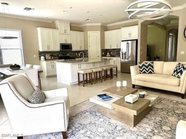 tiled living room featuring a chandelier, ornamental molding, and sink