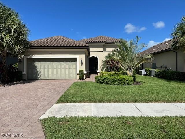 mediterranean / spanish home featuring a front yard and a garage