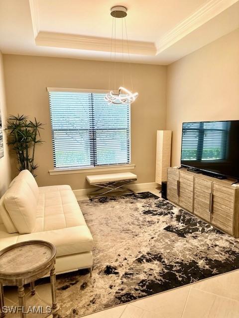 tiled living room with a chandelier and a raised ceiling