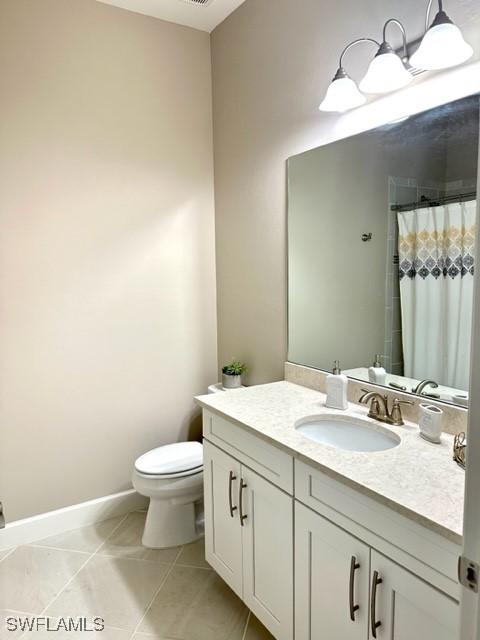 bathroom featuring tile patterned flooring, vanity, curtained shower, and toilet