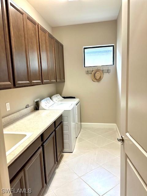 laundry room featuring separate washer and dryer, sink, light tile patterned floors, and cabinets