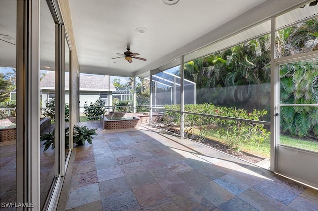 unfurnished sunroom with ceiling fan