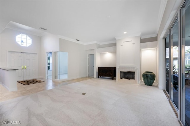 unfurnished living room with a towering ceiling, light colored carpet, and ornamental molding