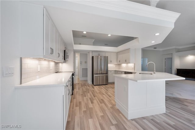 kitchen featuring white cabinets, a kitchen breakfast bar, light wood-type flooring, appliances with stainless steel finishes, and tasteful backsplash