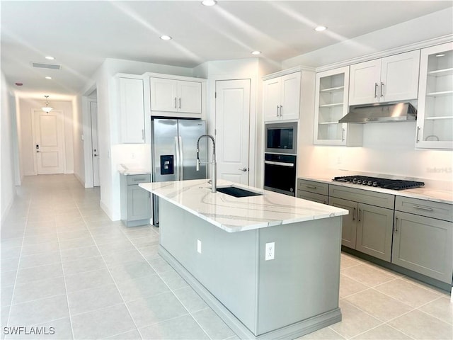 kitchen with a kitchen island with sink, sink, light tile patterned floors, and appliances with stainless steel finishes