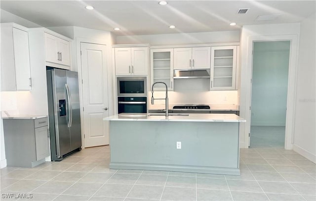 kitchen with light tile patterned flooring, sink, white cabinetry, an island with sink, and stainless steel appliances