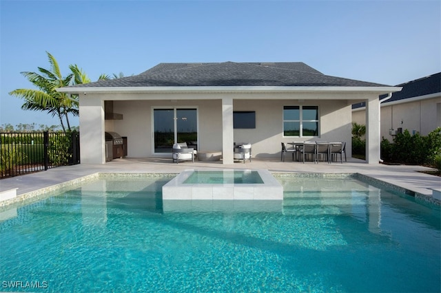 rear view of house with exterior kitchen, a swimming pool with hot tub, a bar, and a patio area