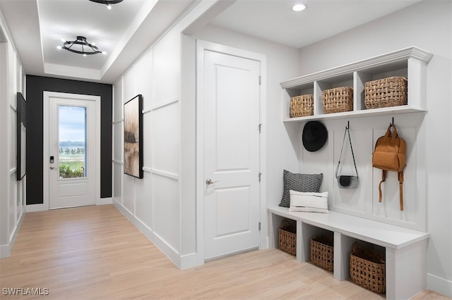 mudroom featuring a raised ceiling and light hardwood / wood-style floors