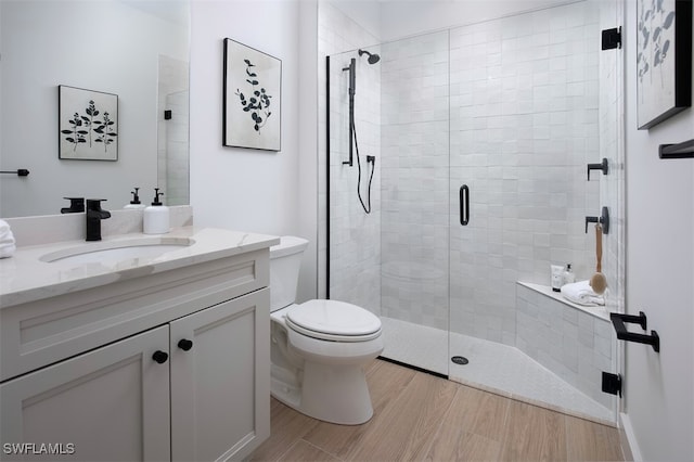 bathroom featuring vanity, hardwood / wood-style flooring, a shower with shower door, and toilet