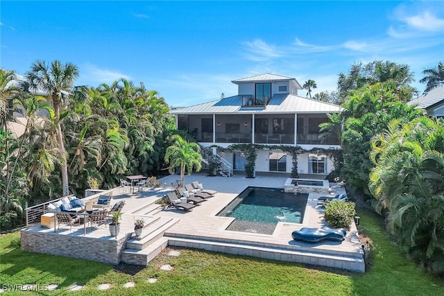 rear view of house with a pool with hot tub, a lawn, a patio area, and a sunroom