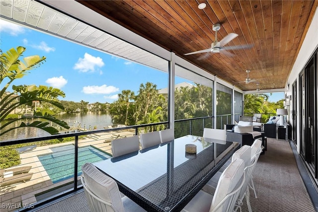 sunroom with ceiling fan, a water view, plenty of natural light, and wood ceiling