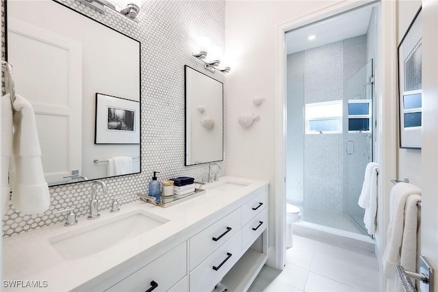 bathroom with decorative backsplash, tile patterned flooring, vanity, tiled shower, and toilet