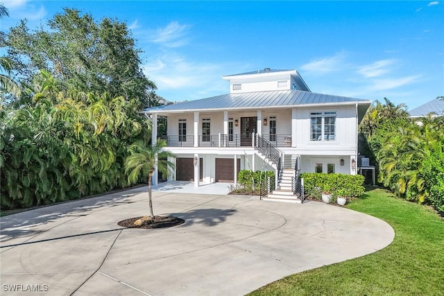 view of front of property featuring a garage, covered porch, and a front yard