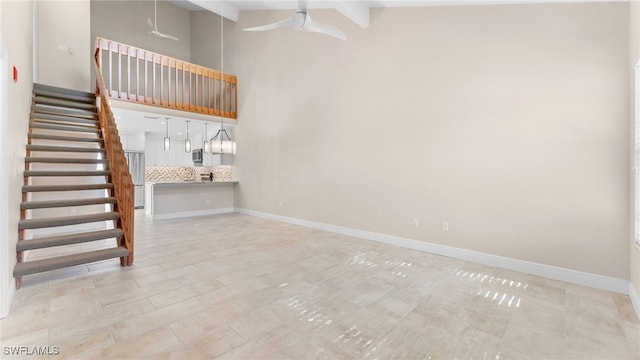 interior space featuring ceiling fan, a towering ceiling, and beamed ceiling