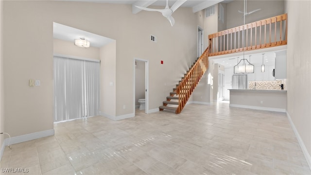 unfurnished living room featuring beam ceiling, high vaulted ceiling, and an inviting chandelier