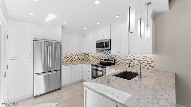 kitchen featuring kitchen peninsula, light stone countertops, stainless steel appliances, sink, and hanging light fixtures