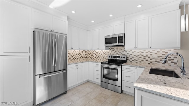 kitchen featuring light stone countertops, appliances with stainless steel finishes, backsplash, sink, and white cabinetry