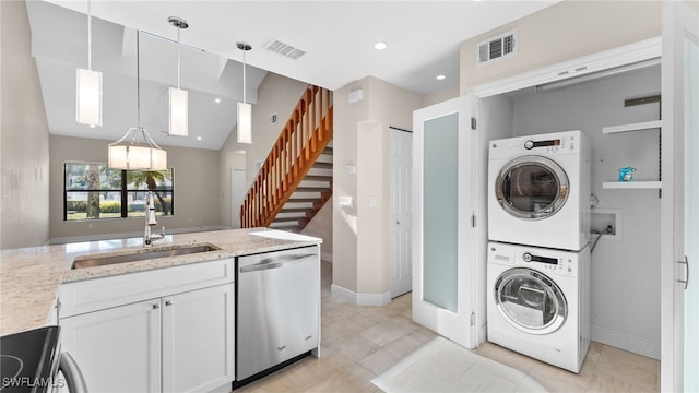 laundry area with light tile patterned flooring, stacked washer and dryer, and sink