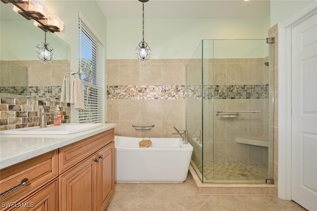 bathroom with tile patterned flooring, vanity, separate shower and tub, and tile walls