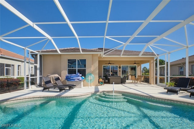 view of pool featuring outdoor lounge area, glass enclosure, ceiling fan, and a patio area