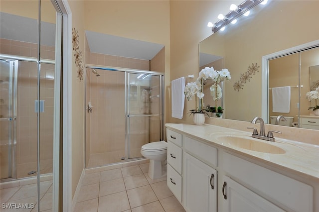 bathroom featuring tile patterned flooring, vanity, toilet, and a shower with shower door