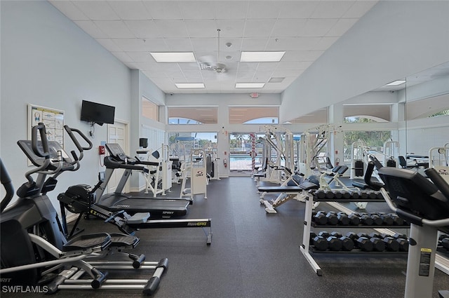 exercise room with a paneled ceiling and a high ceiling