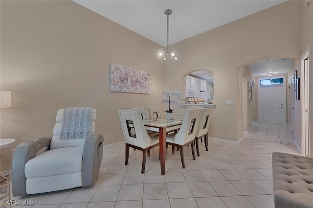 dining area with light tile patterned floors, a chandelier, and vaulted ceiling