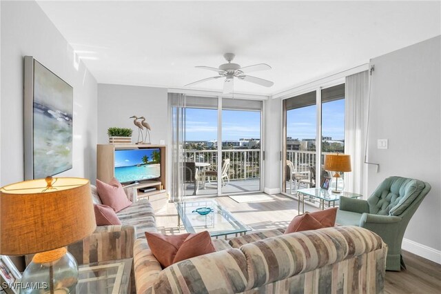 living room with light hardwood / wood-style floors, a wall of windows, and ceiling fan