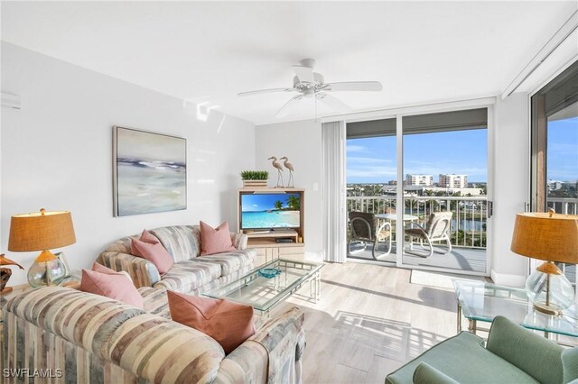 living room featuring expansive windows, light hardwood / wood-style floors, a wealth of natural light, and ceiling fan