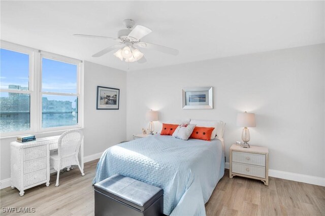 bedroom featuring ceiling fan, light hardwood / wood-style flooring, and a water view