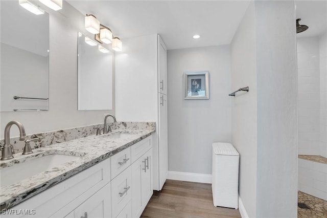 full bathroom featuring wood finished floors, walk in shower, a sink, and baseboards