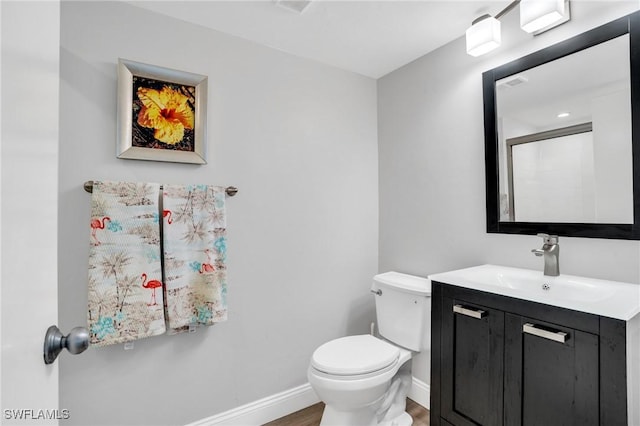 bathroom with toilet, an enclosed shower, vanity, wood finished floors, and baseboards