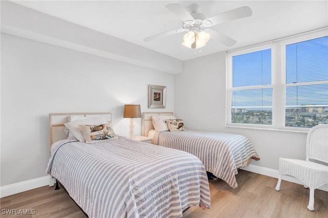 bedroom featuring light wood-style floors, baseboards, and a ceiling fan