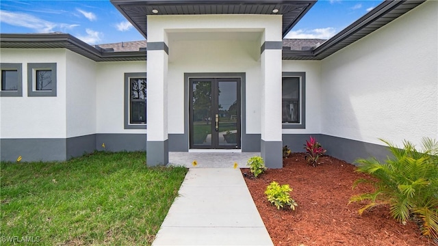 view of exterior entry with a lawn and french doors