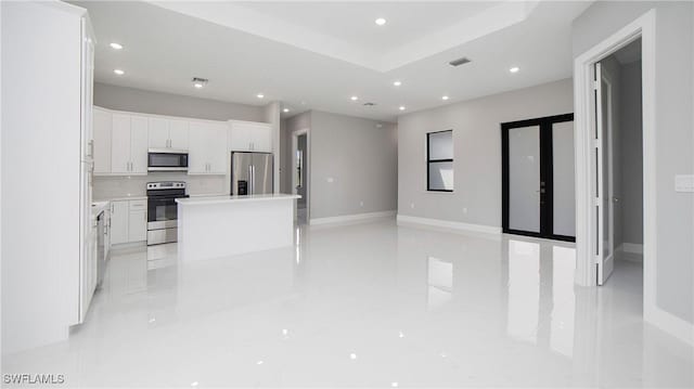 kitchen featuring a center island, french doors, tasteful backsplash, white cabinets, and appliances with stainless steel finishes