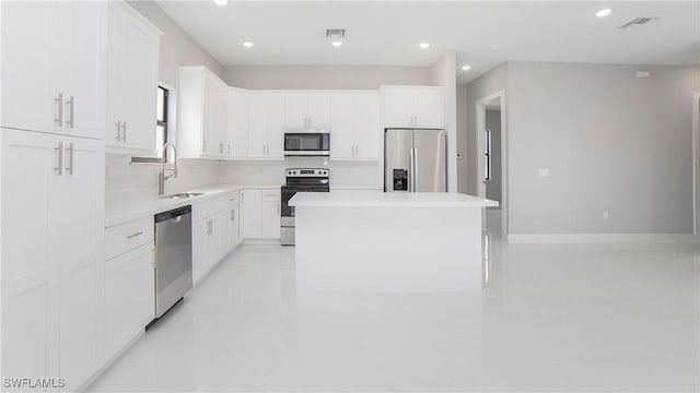 kitchen featuring white cabinetry, sink, a center island, tasteful backsplash, and appliances with stainless steel finishes