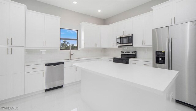 kitchen with white cabinets, backsplash, stainless steel appliances, and a kitchen island