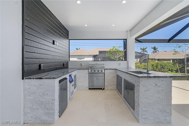 view of patio / terrace with a lanai, a grill, sink, and exterior kitchen