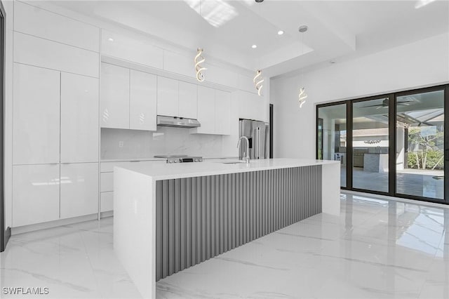 kitchen with white cabinetry, decorative backsplash, pendant lighting, a kitchen island with sink, and high end fridge