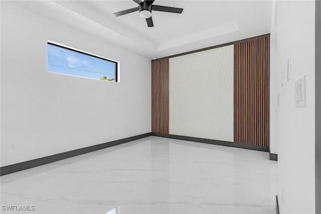 empty room featuring a raised ceiling and ceiling fan