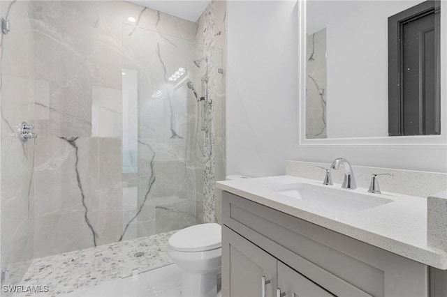 bathroom with tiled shower, vanity, and toilet