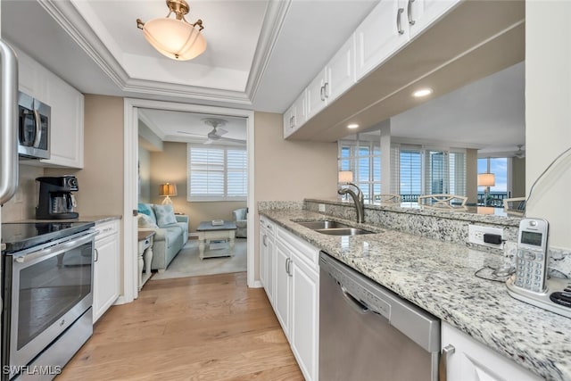 kitchen with light stone countertops, appliances with stainless steel finishes, sink, light hardwood / wood-style floors, and white cabinetry