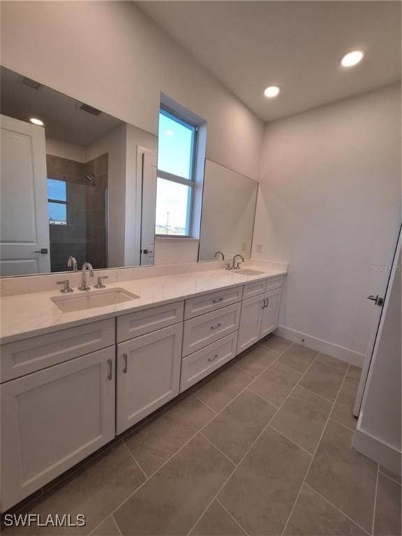 bathroom with tile patterned floors, vanity, and a tile shower