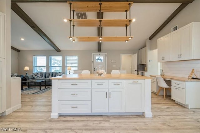 kitchen featuring backsplash, light hardwood / wood-style flooring, white cabinets, and lofted ceiling with beams