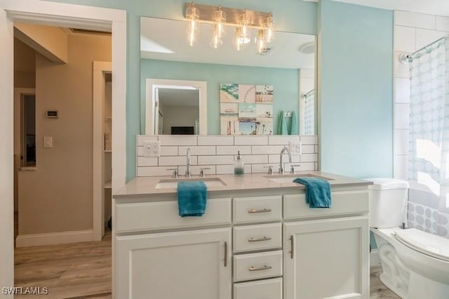 bathroom featuring tasteful backsplash, vanity, wood-type flooring, toilet, and curtained shower