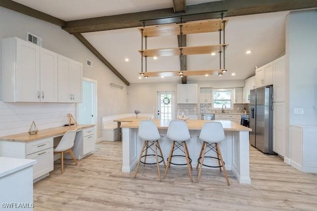 kitchen featuring backsplash, stainless steel fridge, white cabinets, and a kitchen island